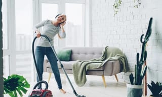 Person cleaning a bright modern living room, maintaining a healthy home environment
