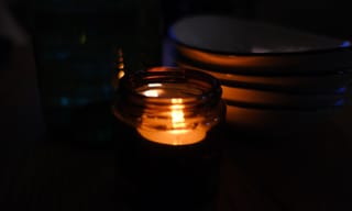 Lit candle with a faint wisp of smoke in a living room setting
