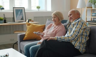 An older couple relaxing together on a sofa in a bright, airy living room