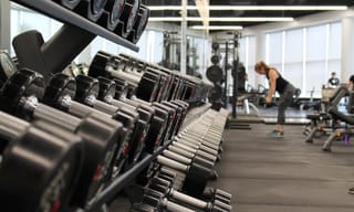 Dumbbell rack in a gym with exercise equipment and natural light. Photo from Unsplash