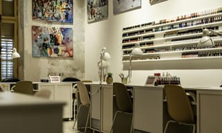 The interior of a modern nail salon with manicure stations and a wall of nail polish bottles