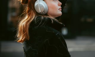 Person wearing over-ear headphones while walking through a busy city street