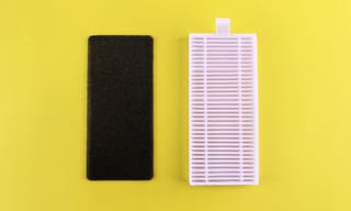 A dirty carbon pre-filter next to a clean white HEPA filter on a yellow background