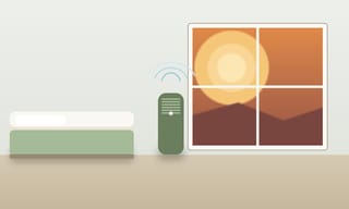 A sealed bedroom with an air purifier running during a smoky orange wildfire afternoon visible through the window