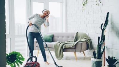 Person cleaning a bright modern living room, maintaining a healthy home environment