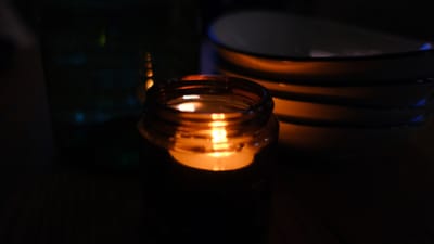 Lit candle with a faint wisp of smoke in a living room setting