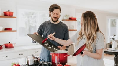 Couple cooking together in a modern kitchen with pots on the stove - Photo by Becca Tapert on Unsplash