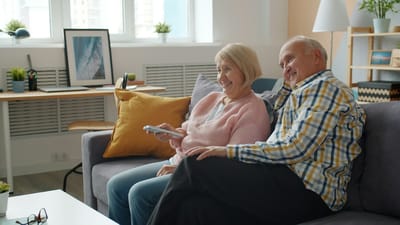 An older couple relaxing together on a sofa in a bright, airy living room