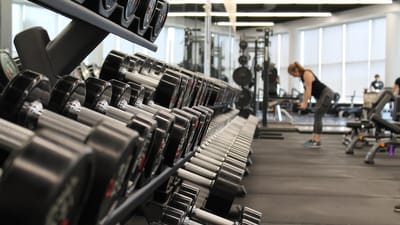 Dumbbell rack in a gym with exercise equipment and natural light. Photo from Unsplash