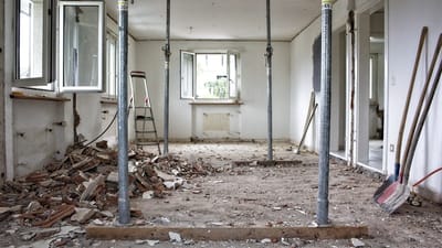 Home renovation in progress with paint cans, sanding equipment, and visible dust particles in the air