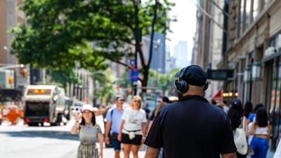 Commuter wearing over-ear headphones in a crowded city street