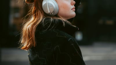 Person wearing over-ear headphones while walking through a busy city street