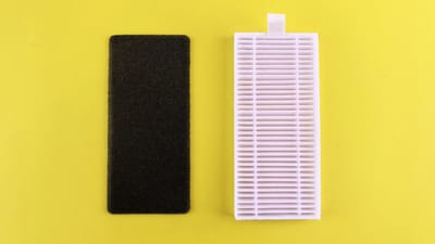 A dirty carbon pre-filter next to a clean white HEPA filter on a yellow background