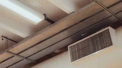 Person checking an indoor air quality monitor displaying CO2 and PM2.5 readings