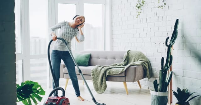 Person cleaning a bright modern living room, maintaining a healthy home environment