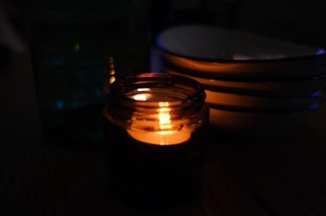 Lit candle with a faint wisp of smoke in a living room setting