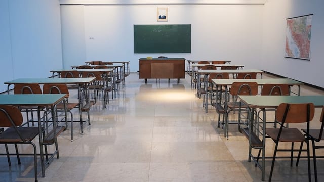 Empty classroom with rows of desks and a green chalkboard - Photo by Ivan Aleksic on Unsplash