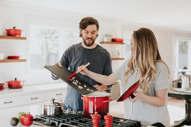Couple cooking together in a modern kitchen with pots on the stove - Photo by Becca Tapert on Unsplash