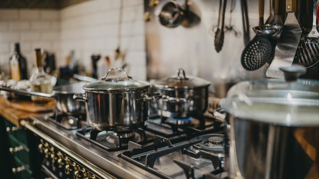 Pots on a lit gas range burner in a home kitchen