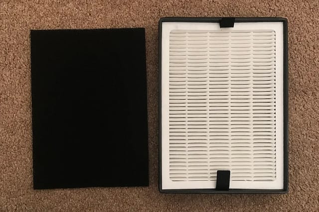 Dark activated carbon filter and white pleated HEPA filter side by side showing the two main air purifier filter types