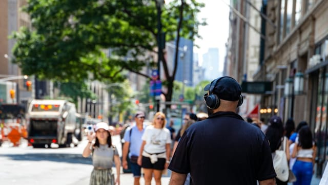 Commuter wearing over-ear headphones in a crowded city street