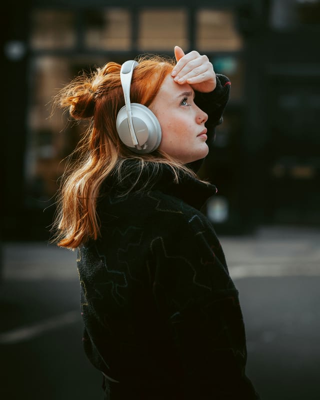Person wearing over-ear headphones while walking through a busy city street